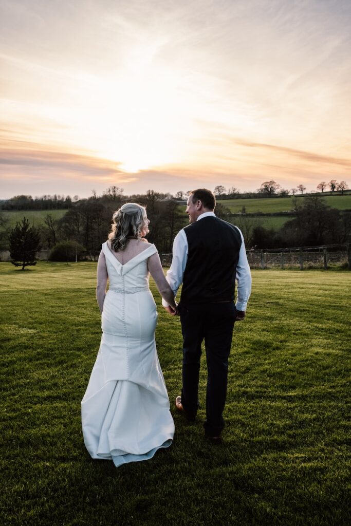 Bride and groom walk into the sunset 